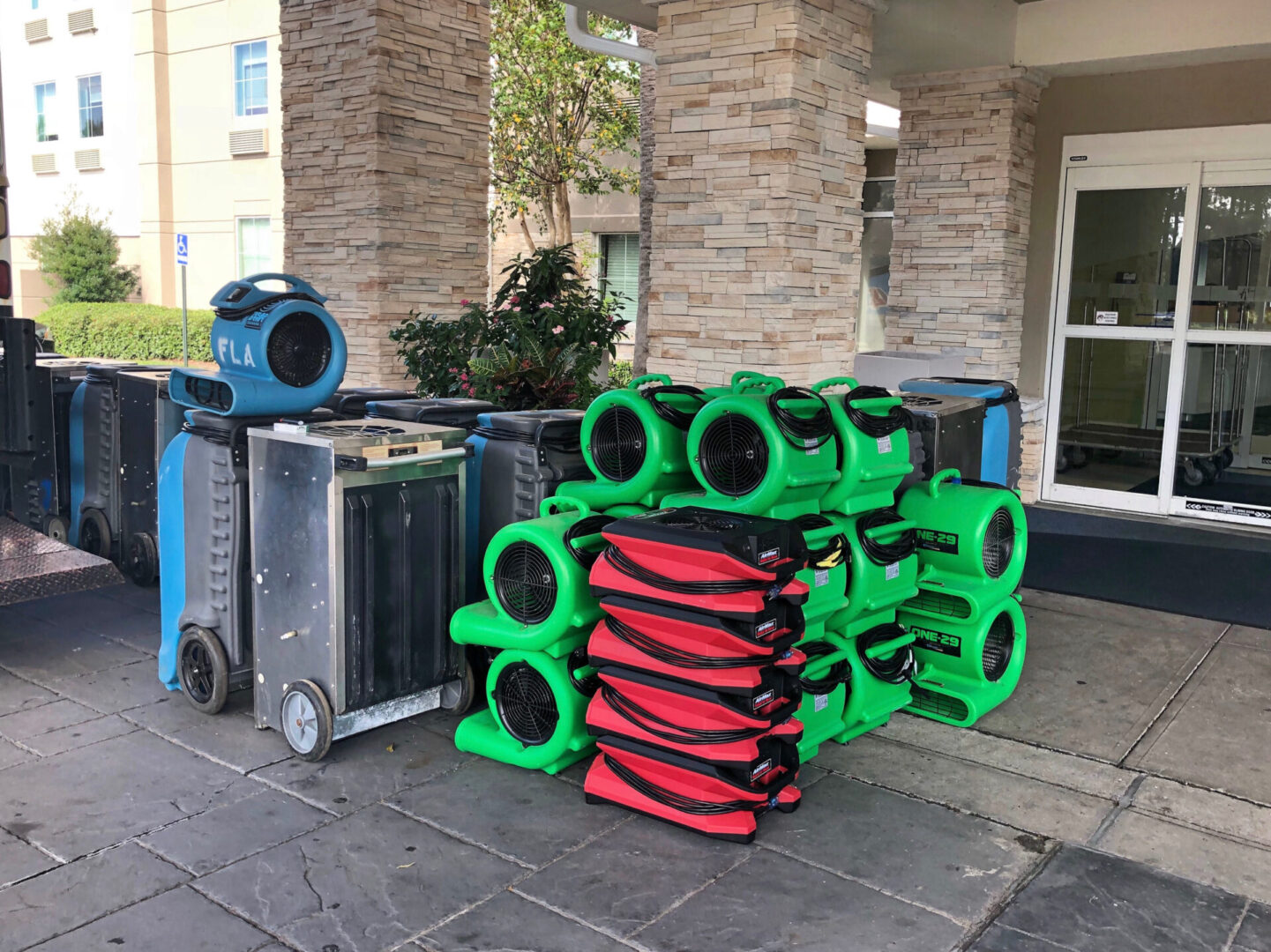 Stacked industrial air movers outside building entrance.