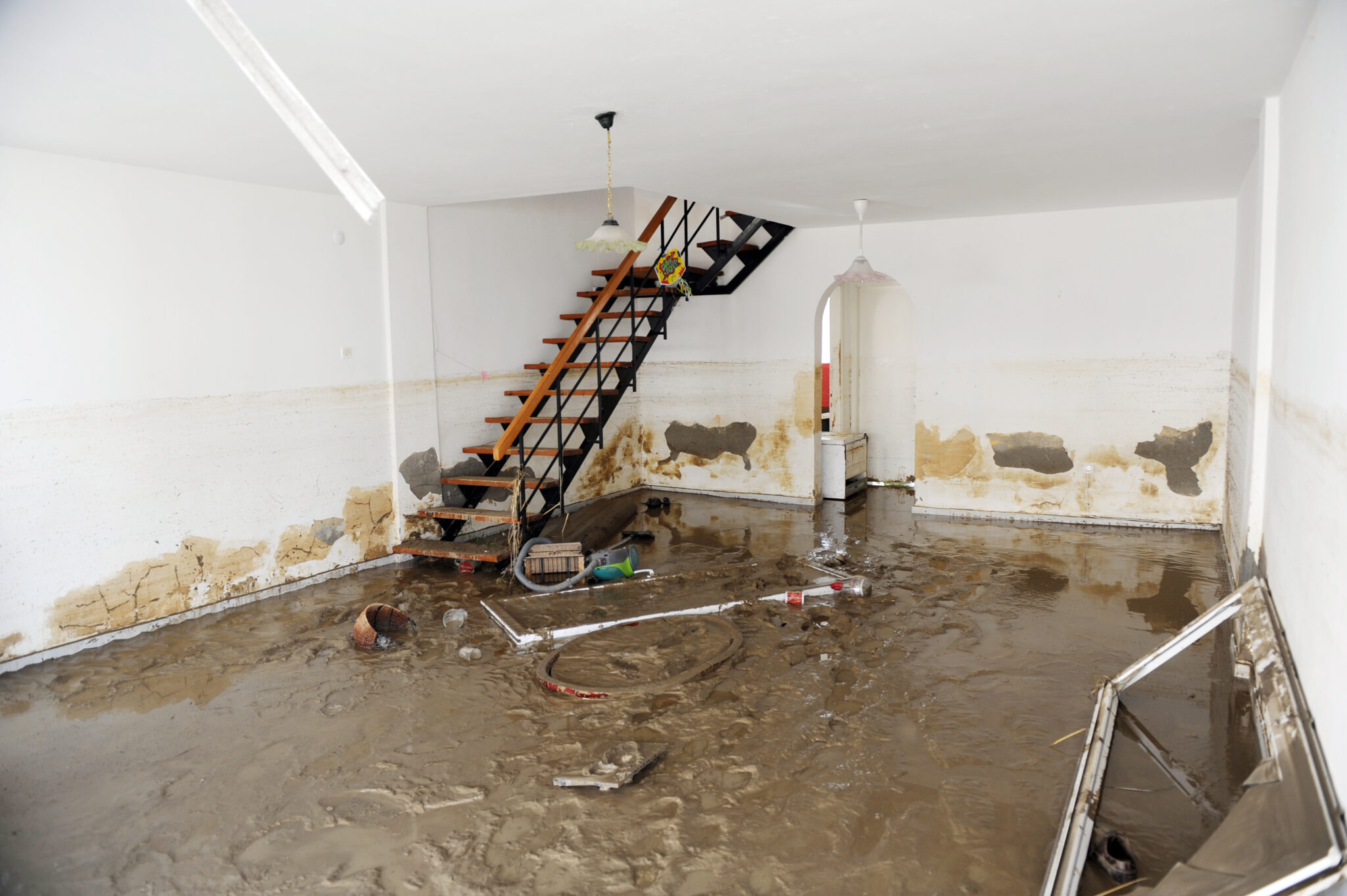 Flooded basement with damaged interior and stairs.