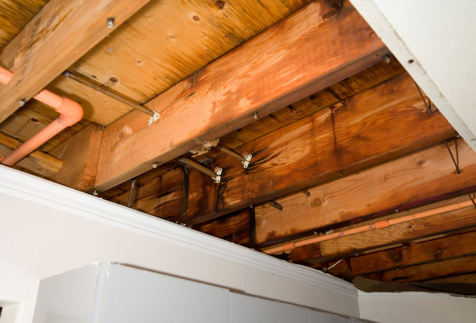 Exposed wooden ceiling beams with pipes visible.
